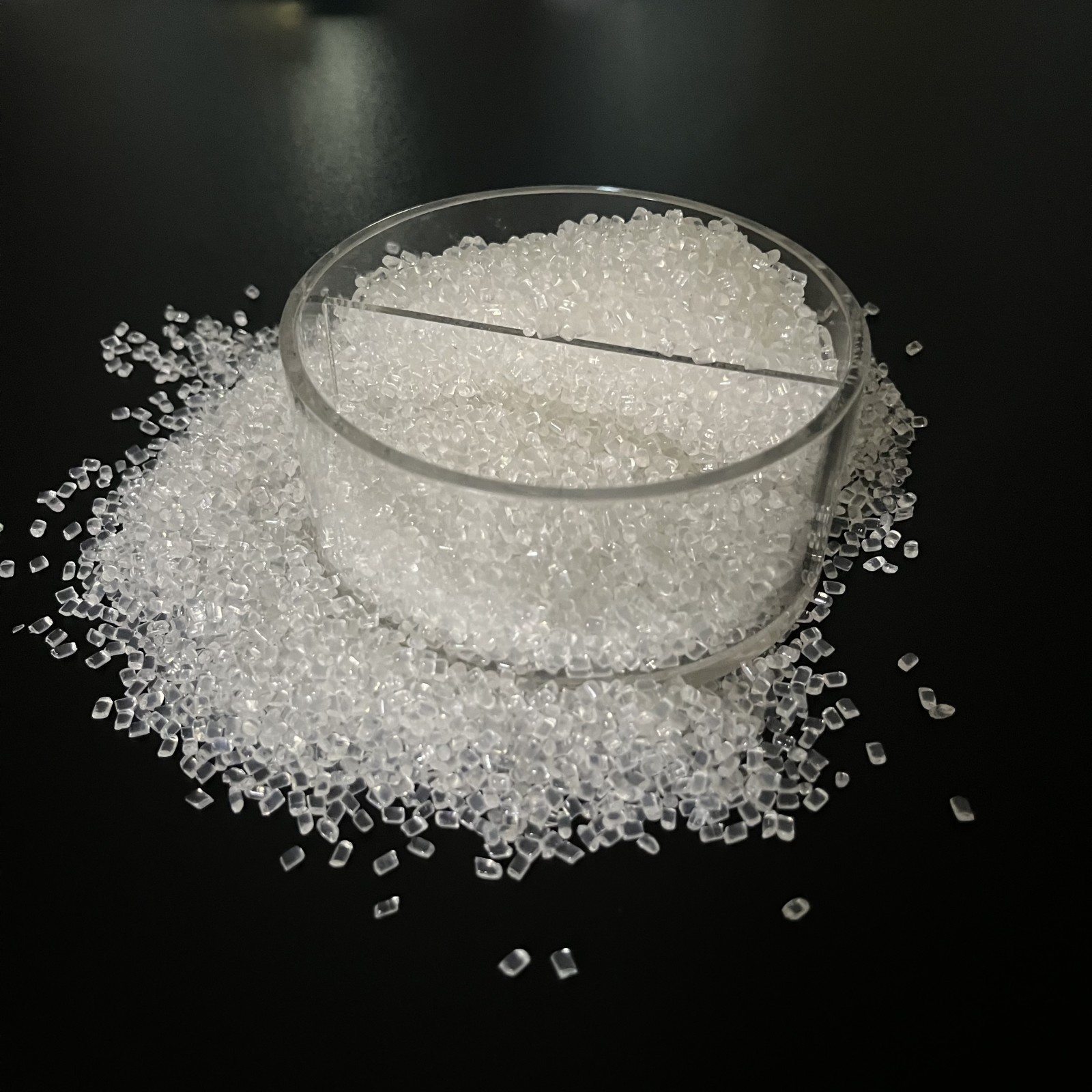 Transparent impact modifier granules displayed in a clear sample ring on a black background